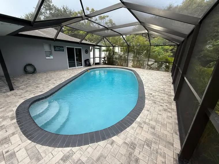 Seven-inch aluminum super gutter running along the roofline where a pool cage meets the house
