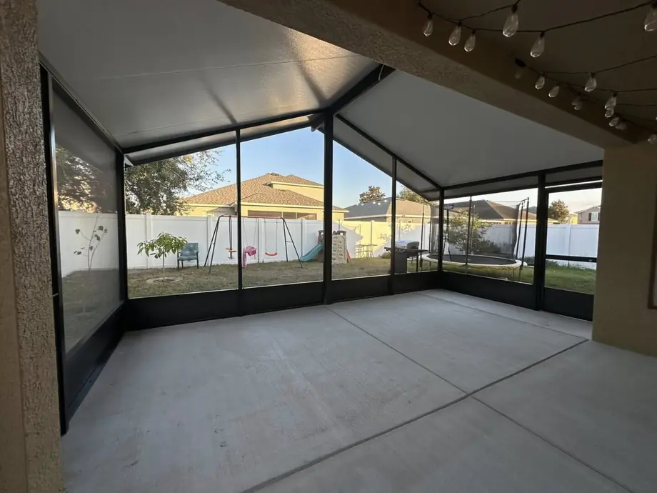 Pool cage enclosure with a mansard roofline and wide screen panels