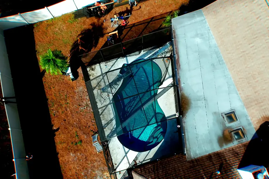 Aerial view of a pool enclosure mid-rescreen with new mesh panels going in
