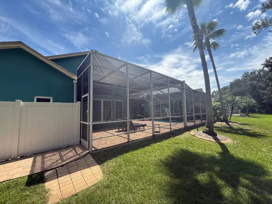 Completed aluminum pool cage enclosure over a screened pool deck at a Florida home
